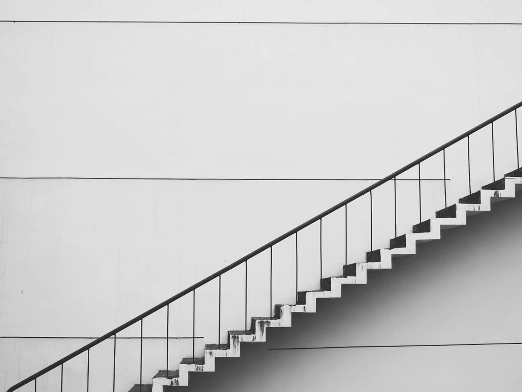 A black and white picture of a staircase over a white wall
